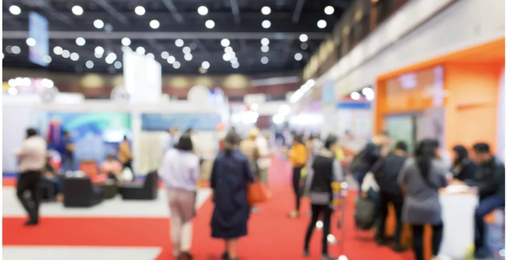 Allée d’un salon professionnel à Paris avec des visiteurs en interaction sur des stands.