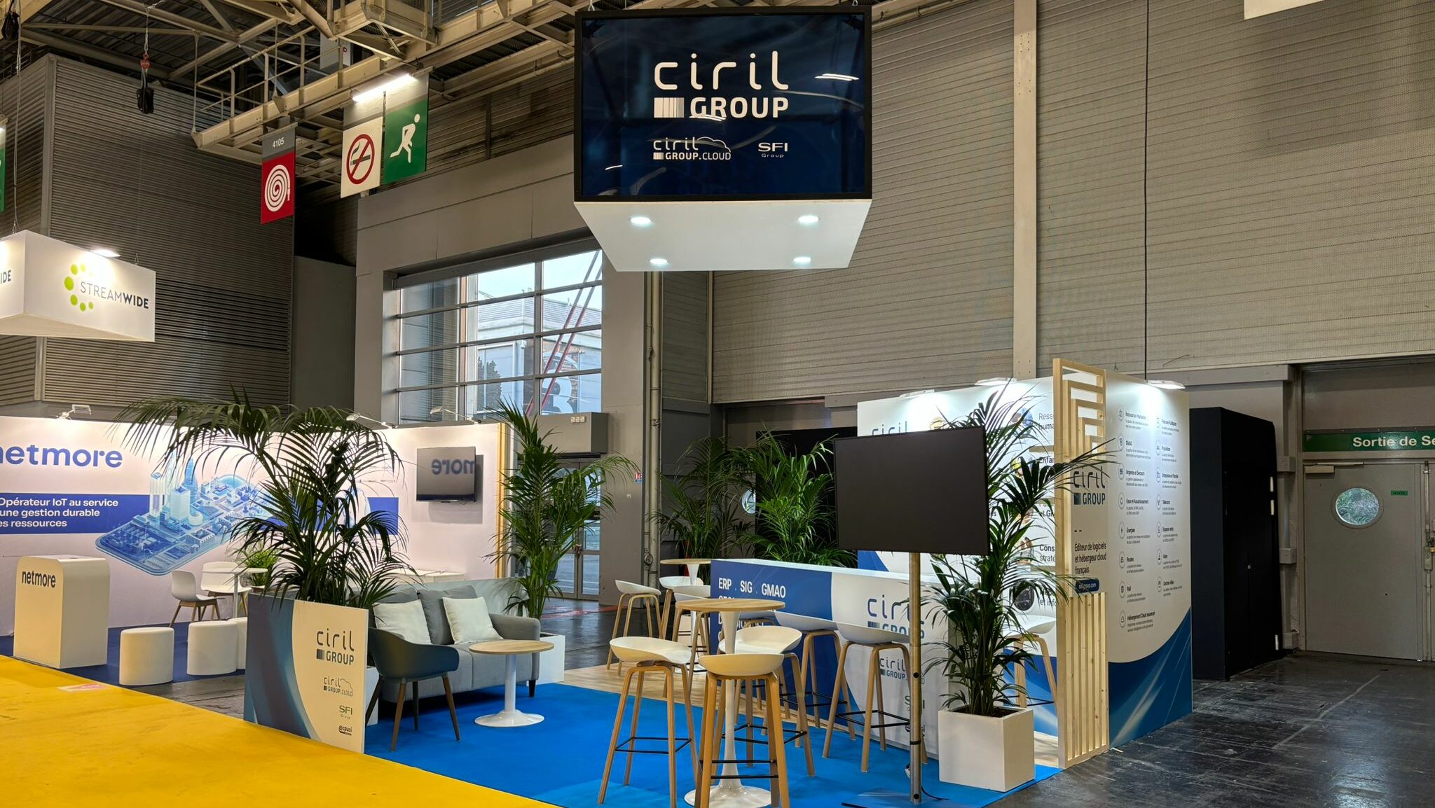 Vue d’ensemble du stand Ciril Group au Salon des Maires, avec sol bleu et signalétique suspendue.